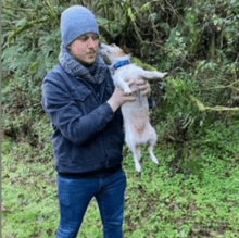 a man is holding a small dog in his arms and the dog is licking the man 's face