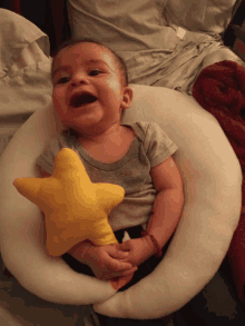 a baby laying on a pillow with a yellow star