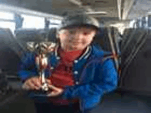 a young boy is holding a trophy in his hand while sitting on a bus .