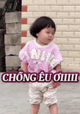 a little girl standing in front of a brick wall with a sticker that says zoo