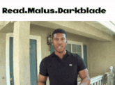 a man in a black shirt stands in front of a house with the words read.malus.darkblade below him