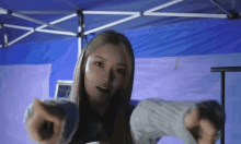 a woman is pointing at the camera while standing under a tent .