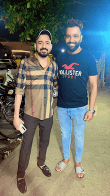 a man wearing a hollister sport shirt poses with another man