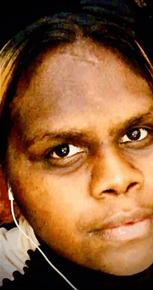 a close up of a person 's face with ear buds around their neck