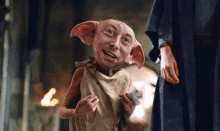 a dobby from harry potter is smiling and holding a card