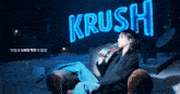 a woman sits in a chair drinking from a bottle of krush