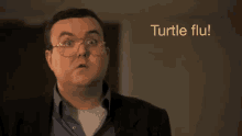 a man wearing glasses and a suit says " turtle flu " in front of him