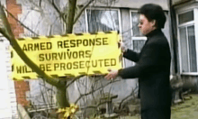 a man holds up a yellow sign that says armed response survivors will be prosecuted