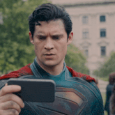 a man in a superman costume is taking a picture of himself with a cell phone