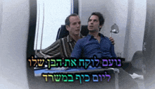 two men are sitting in front of a window with a sign in hebrew behind them