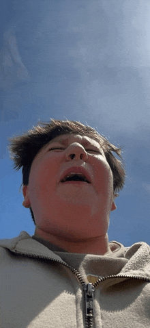 a person with a zipper on their jacket looks up at the sky