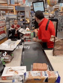 a man in a red shirt is behind a counter in a grocery store with a bag of blanco bread on it