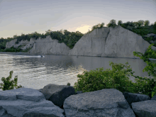 a boat is floating on the water near a rocky cliff