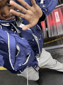 a person wearing a blue jacket has their hand up in front of a sign that says large