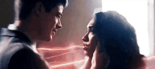 a man and a woman are looking into each other 's eyes while a flash is behind them .