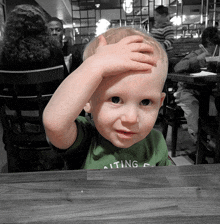 a young boy wearing a green shirt that says sitting on it