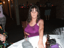 a woman in a purple tank top sits at a table in front of a sign that reads rooms