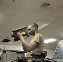 a man in a military uniform is working on a device with a yellow sticker on it