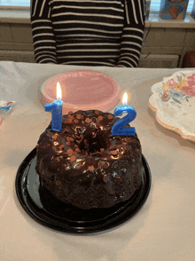 a chocolate bundt cake with two blue candles on it