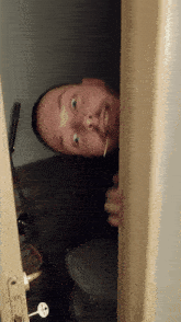 a man peeking out from behind a door holding a toothpick