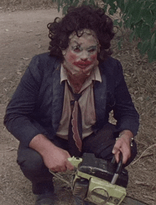 a man in a suit and tie is kneeling down with a chainsaw