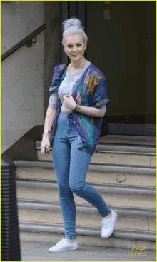 a woman wearing a purple shirt and blue jeans is walking down a set of stairs