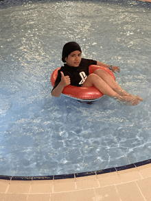 a young boy in a playstation shirt is giving a thumbs up in a swimming pool