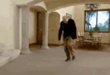 a man in a black jacket is dancing in a room