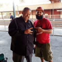 two men are posing for a picture and one has a sticker on his shirt that says ' de yogurt '