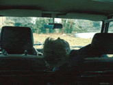 a man sleeping in the back seat of a car with a rear view mirror
