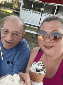 a man and a woman eating ice cream in front of a house