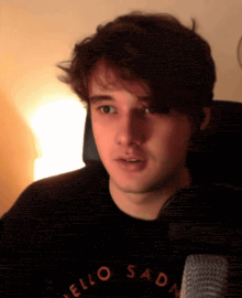 a man wearing a black shirt that says hello sad
