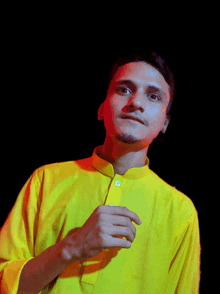 a man in a yellow shirt looks at the camera with a black background