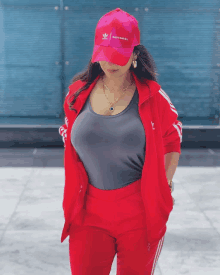 a woman wearing a red jacket and a pink hat with the word adidas on it