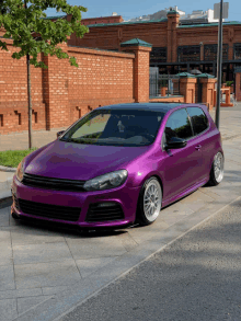 a purple car is parked on the sidewalk in front of a brick building