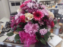 a bunch of pink flowers in a vase with a pink ribbon