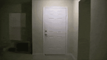a white door is open in a dark room with a light shining on it .