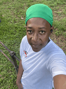 a woman wearing a white shirt and a green headband takes a selfie in the grass