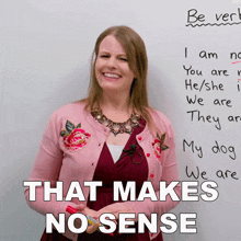 a woman in a pink cardigan stands in front of a white board with the words that makes no sense written on it