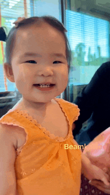 a little girl in a yellow dress is smiling and looking at the camera