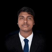 a man in a suit and tie looks at the camera with a black background