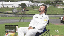 a man is sitting in a chair with his eyes closed in front of a race track