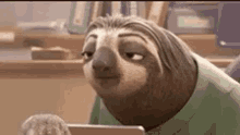 a cartoon sloth is sitting at a desk looking at a laptop .