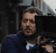 a man with a beard is holding a camera in his hand