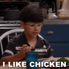 a young boy is sitting at a table with a plate of food and the words i like chicken behind him