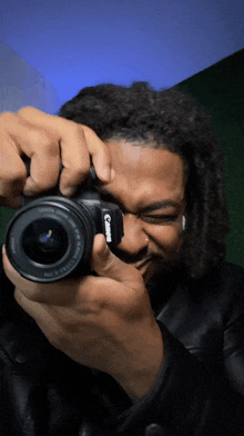 a man taking a picture with a camera that says canon on it