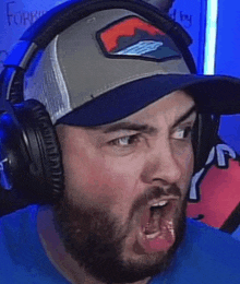 a man with a beard is wearing headphones and a baseball cap .