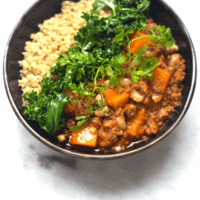 a bowl of food with meat and vegetables including kale and quinoa