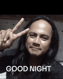 a man with long hair is giving a peace sign with the words good night behind him