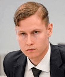 a young man in a suit and tie is sitting at a table .